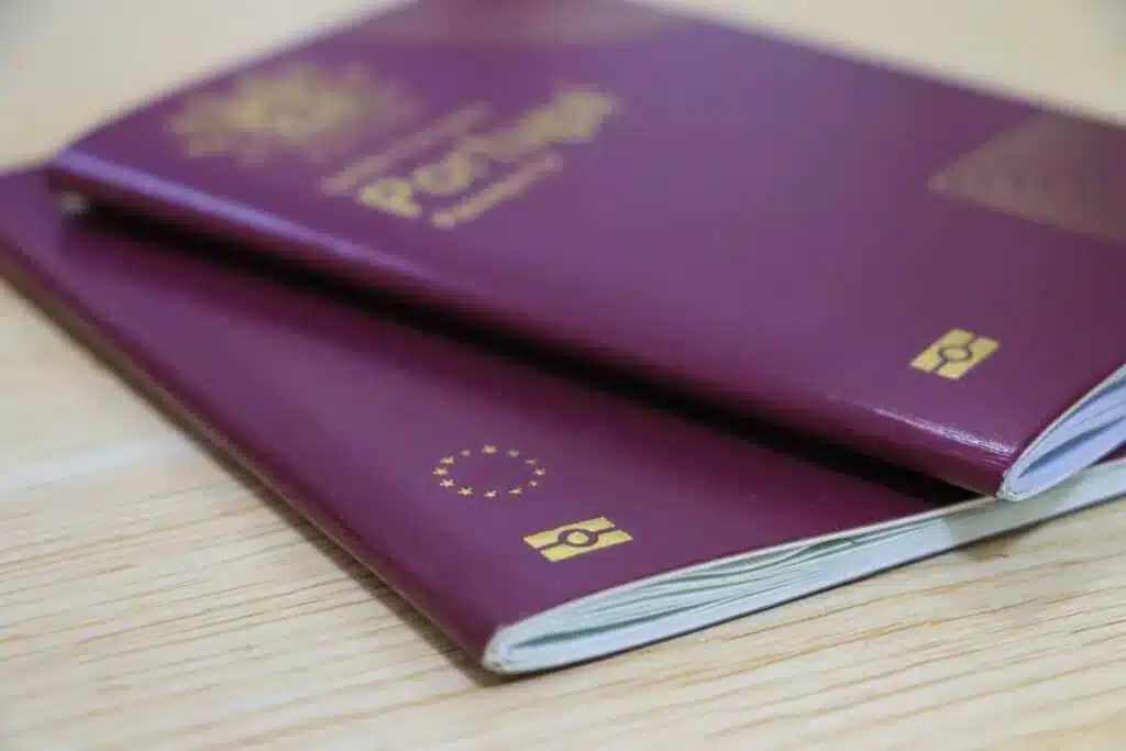 Two Portuguese passports placed on a wooden surface.